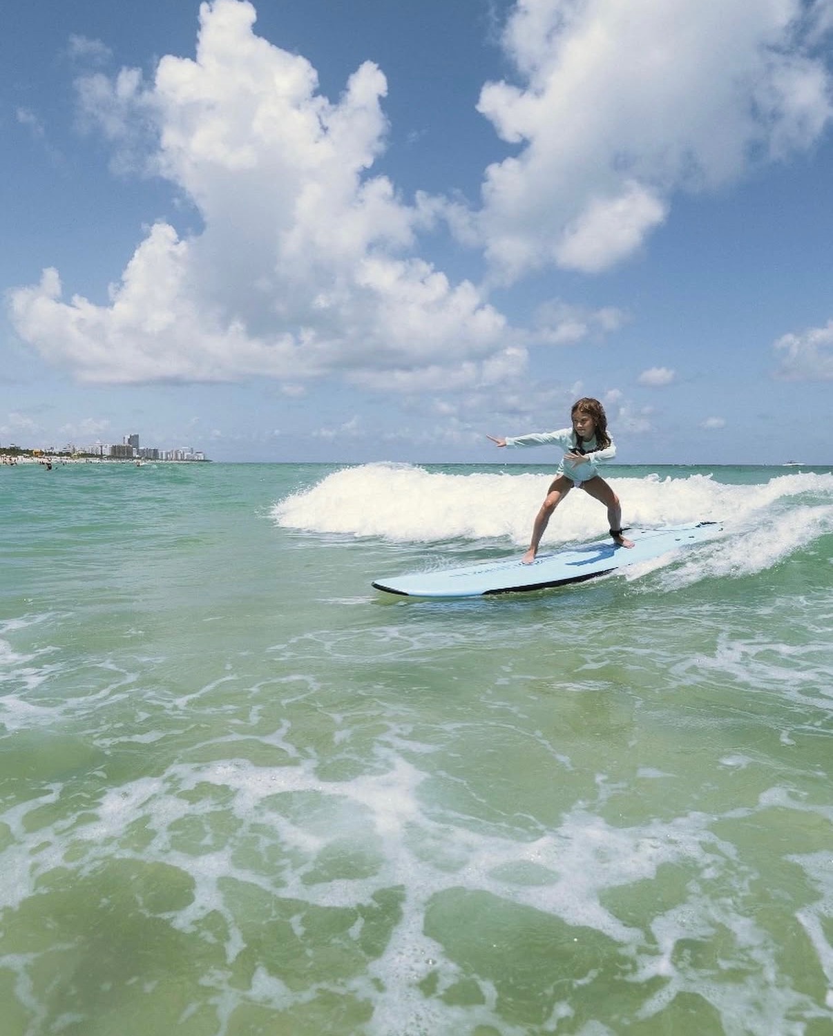 Kids surf lesson in Miami Girl riding a wave on a soft-top surfboard in Miami